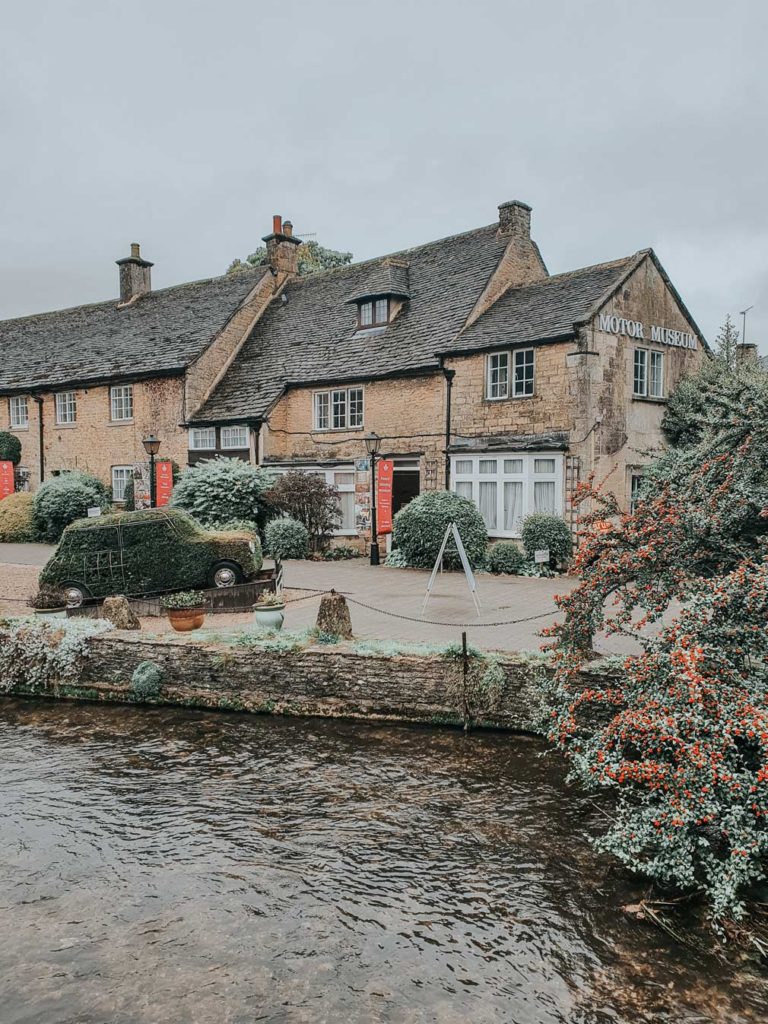 The exterior of the Cotswolds Motor Museum with the River Windrush in the foreground.