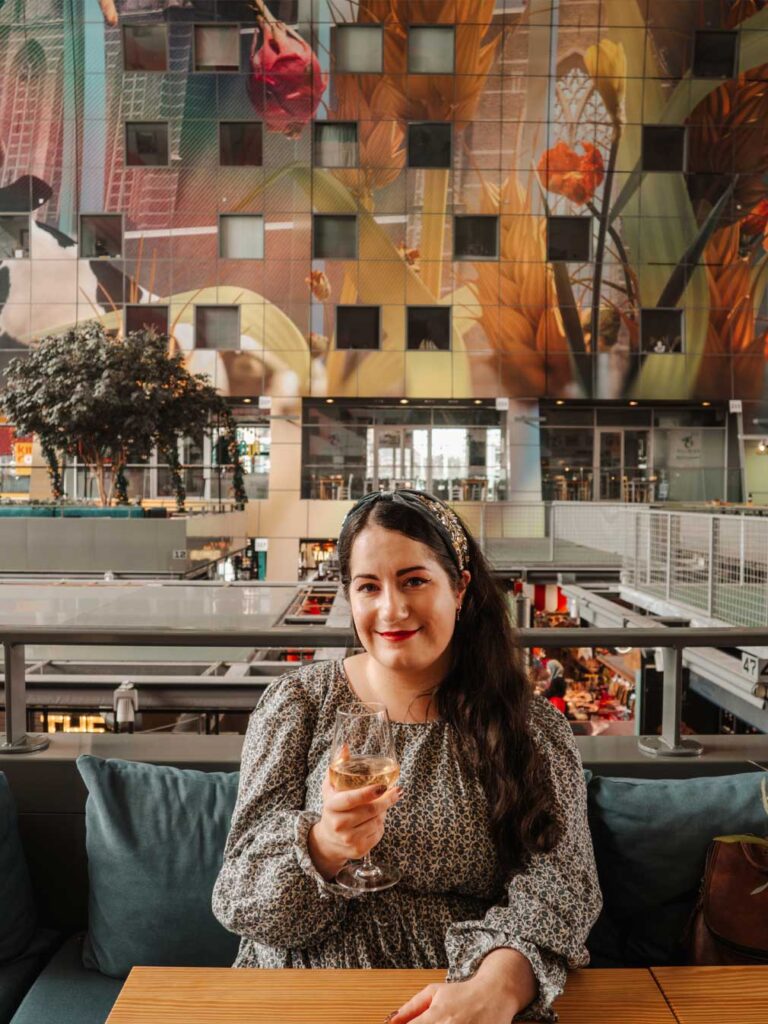 Brunette woman drinking a glass of wine at De Markthal
