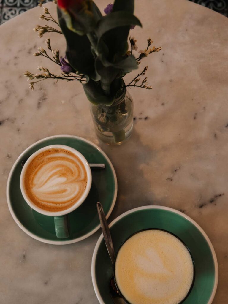 Hot drinks on a marble table at By Lima in Haarlem. The drinks have lovely latte art with a curved pattern.