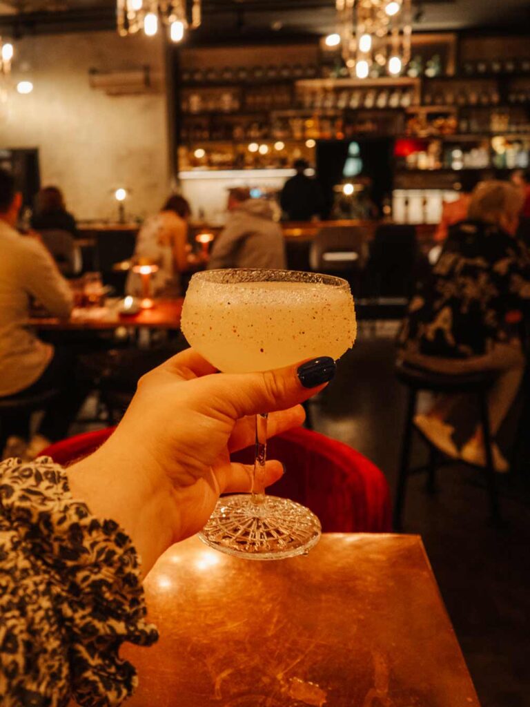 Lauren (the owner of this blog) holding a spicy margarita cocktail at Three Fingers Bar.