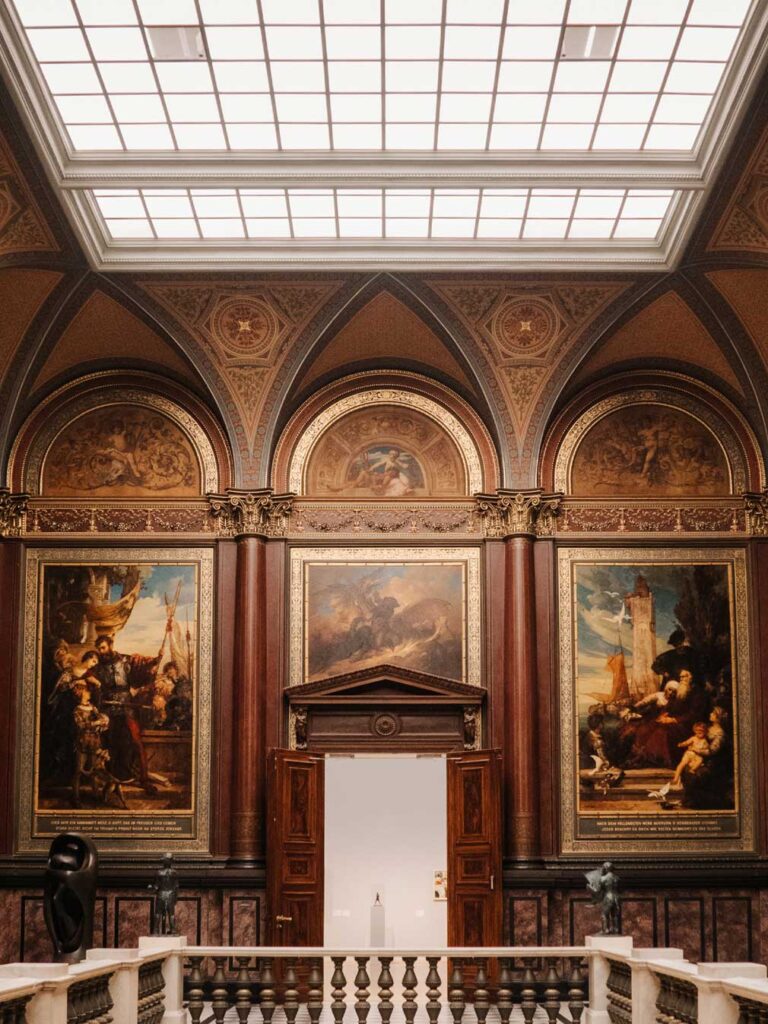 The balcony of Hamburg Kuntsthalle showcasing various paintings elegantly displayed on the walls with patterned ceilings and wooden doors