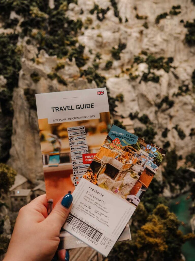 A woman holding a leaflet and ticket for Miniatur Wunderland in Hamburg.