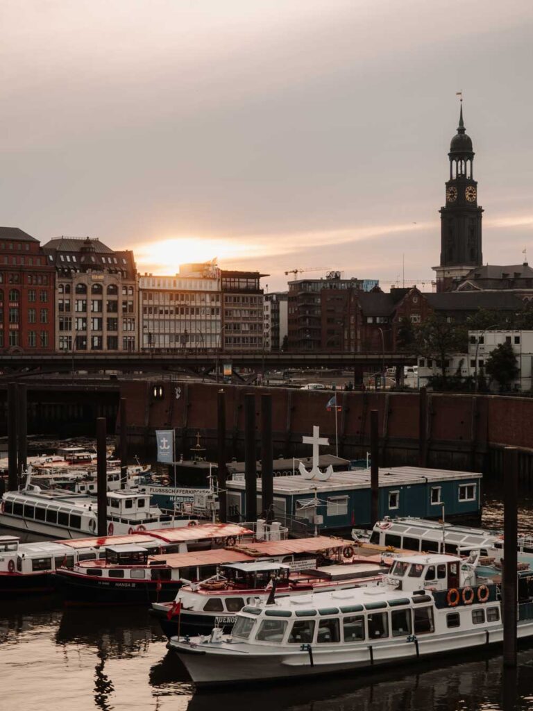 A relaxing port view during sunset featuring several boats gently floating on the water's surface. In the distance, you can see a view of St. Michael's Church.