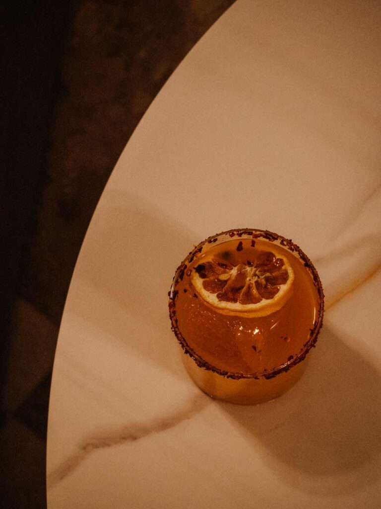 A spicy mangorita cocktail from Sonata Lounge placed on a white marble table.