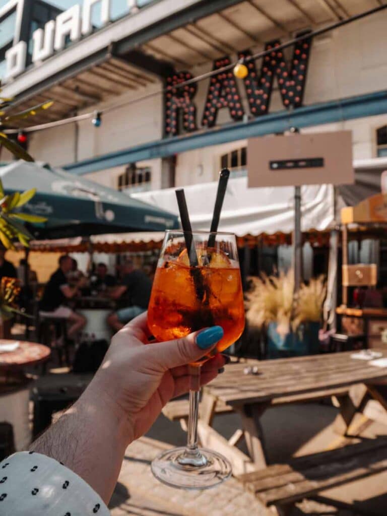 Lauren holding an Aperol Spritz at Raw Bar in Tilburg.